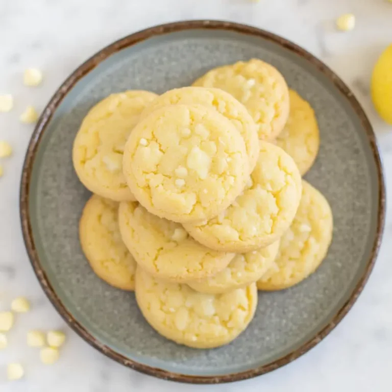 Freshly baked lemon white chocolate cookies on a tray with lemon zest and white chocolate chunks